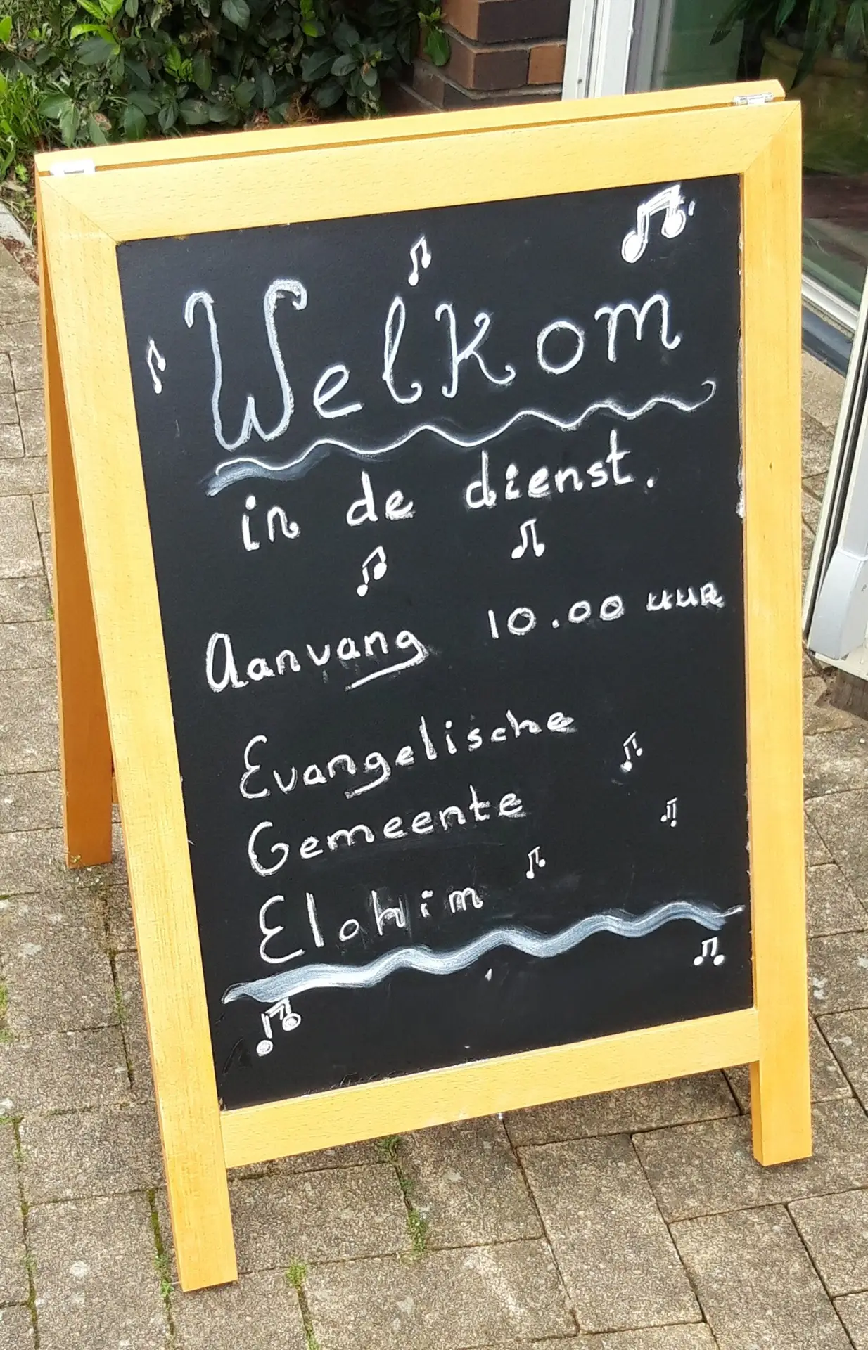 Krijtbord bij de ingang: Welkom in de dienst, aanvang 10.00 uur, Evangelische Gemeente Elohim